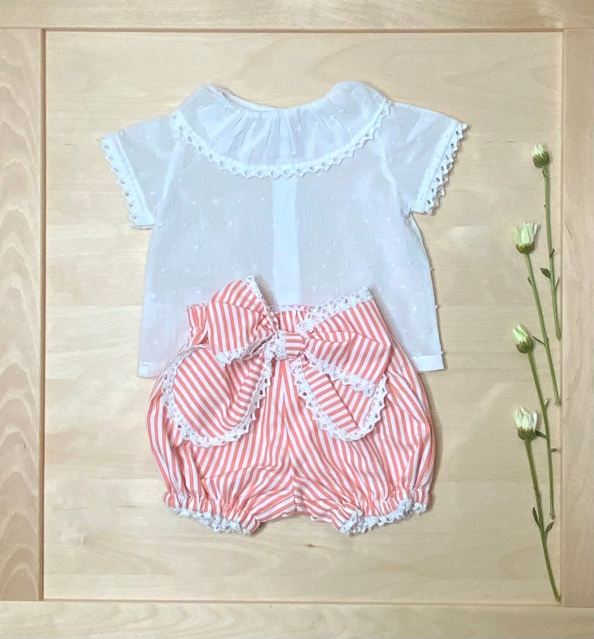 The Coral white plumeti blouse and coral striped bubble shorts set on light wood background — Alfa Baby Boutique