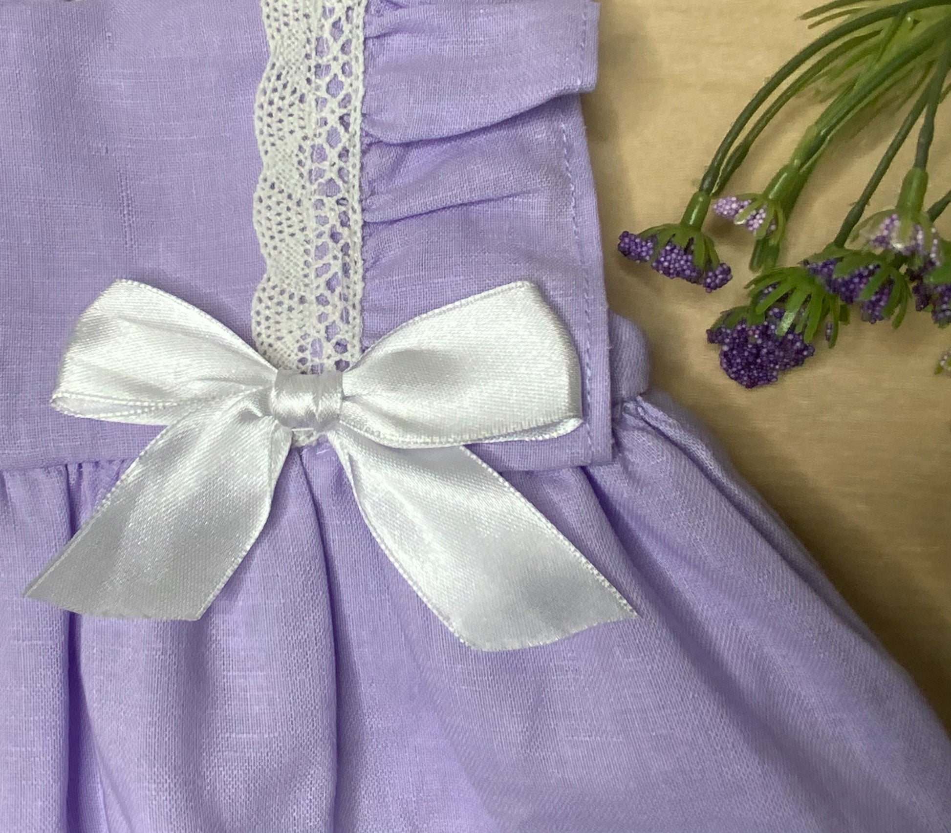 Close-up detail of The Violet lavender linen fabric and lace hem trim, and white bow — Alfa Baby Boutique