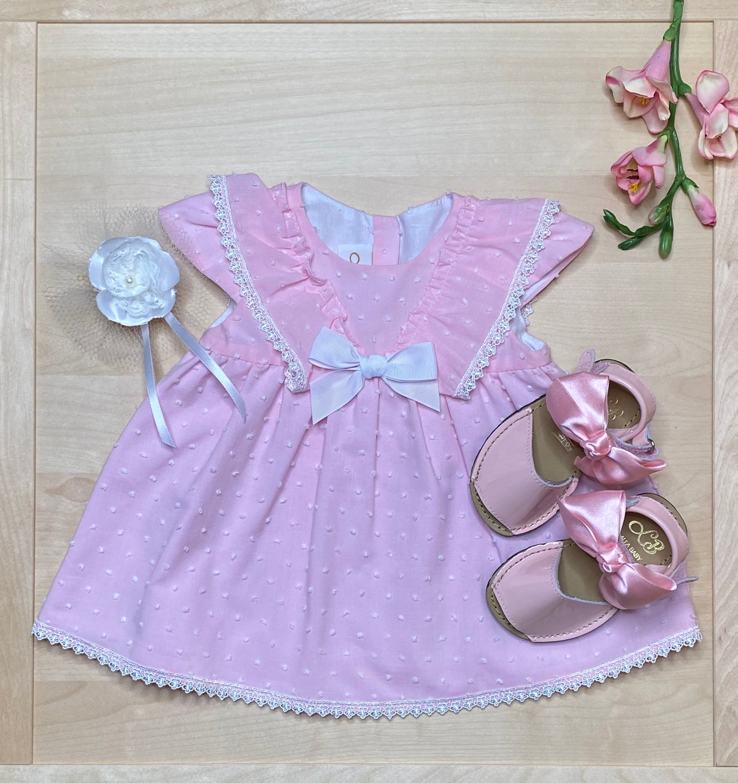 The Peony pink Swiss dot dress and bloomers on light wood background with matching sandals — Alfa Baby Boutique