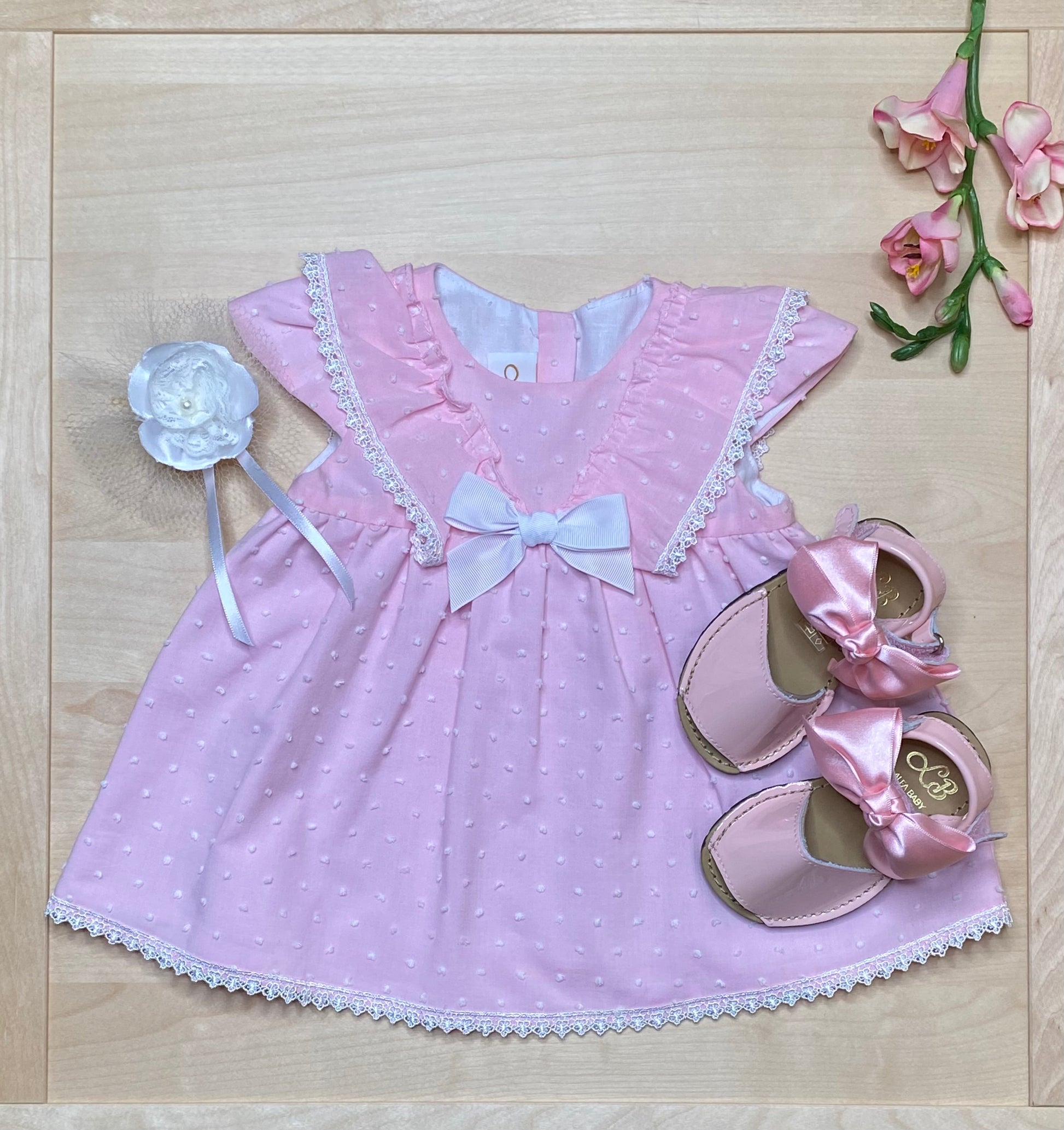 The Peony pink Swiss dot dress and bloomers on light wood background with matching sandals — Alfa Baby Boutique