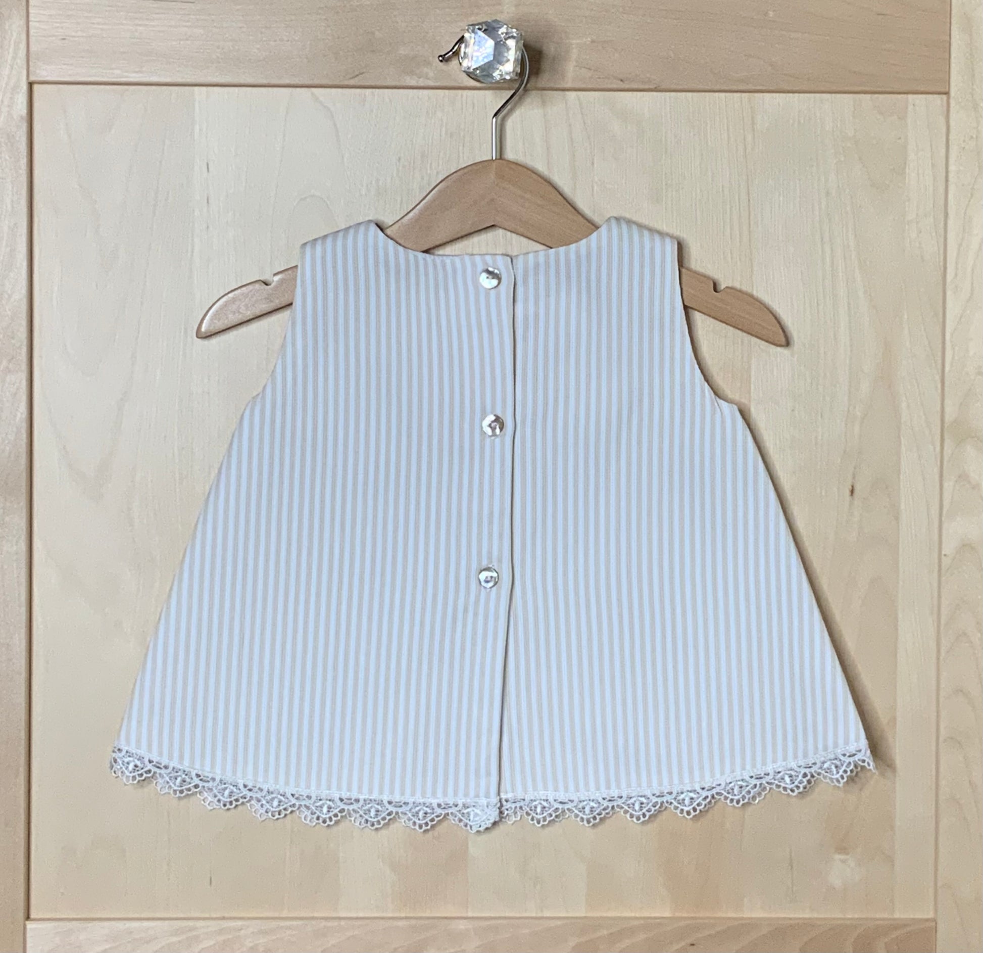 Back view of The Sweet Vanilla ivory striped A-line dress showing button closure and lace hem trim — Alfa Baby Boutique